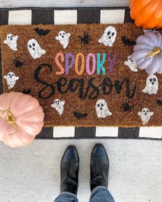 someone is standing in front of a halloween door mat that says spooky season