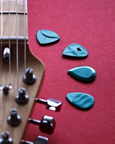 several guitar picks laying next to each other on a red surface with strings in the foreground