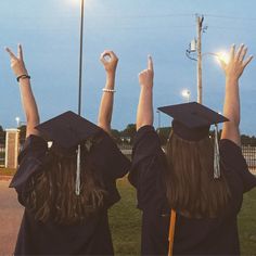 three graduates raising their hands in the air