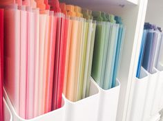 several different colored folders are hanging on a white wall next to each other in a row