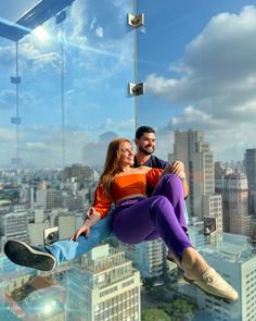 a man and woman sitting on top of a skyscraper