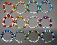 several bracelets with different colored beads are arranged in a row on a gray surface