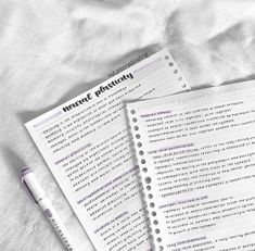 two notebooks sitting next to each other on top of a white sheet with writing