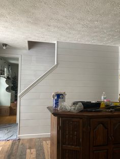 a kitchen with white painted walls and wood flooring on the counter top, next to a wooden cabinet