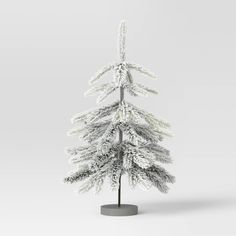 a white christmas tree with snow on it's branches in front of a gray background