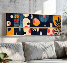 a painting hanging on the wall above a white couch in a room with concrete walls