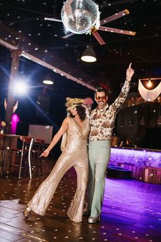 a man and woman dancing on a dance floor at a party with disco balls in the background