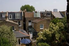 an aerial view of some buildings with trees in the foreground and a blue umbrella