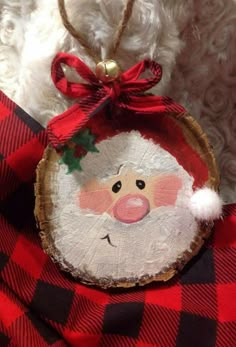 a christmas ornament hanging from a tree slice with a santa clause on it