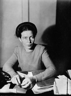 an old black and white photo of a woman sitting at a desk with papers in front of her