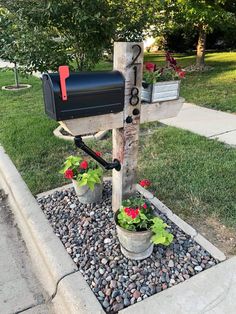 a mailbox sitting on the side of a road with flowers growing out of it