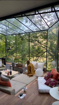 a living room filled with lots of furniture under a large glass ceiling covered in trees