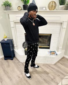 a man standing in front of a fire place wearing black and white patterned sweatpants