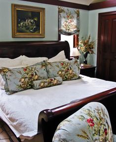 a bed with white sheets and pillows in a bedroom next to a painting on the wall