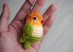 a small crocheted bird keychain in the palm of someone's hand