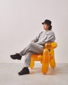 a young man sitting on an orange plastic bench with his feet propped up against the seat