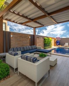 an outdoor living area with couches, chairs and a swimming pool in the background