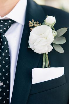 a man wearing a suit and tie with a boutonniere on his lapel