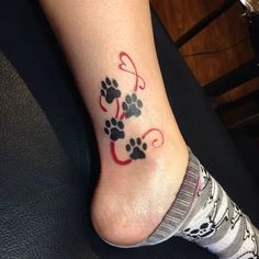 a dog paw tattoo on the foot of a woman's left leg, with red and black ink