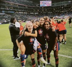 two girls are hugging each other on the field at a soccer game with fans in the stands