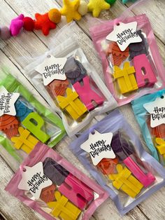 four birthday candles in plastic bags with happy birthday tags on them sitting on a wooden table