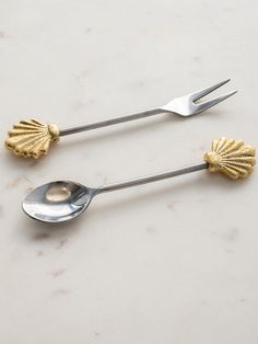 two silver and gold spoons sitting on top of a white counter