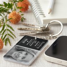 a cell phone and keychain with an image of a woman on it next to flowers