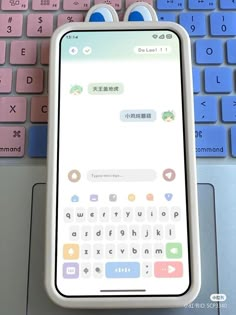 a cell phone sitting on top of a laptop keyboard next to a pink and blue keyboard