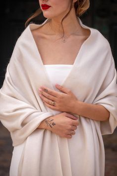 a woman wearing a white shawl with tattoos on her arm