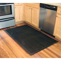 a kitchen area with a stove, dishwasher and oven door mat on the floor