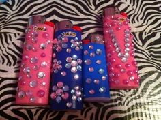 three lighters are sitting on a zebra print tablecloth with silver and pink sequins