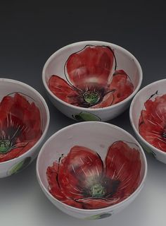 four white bowls with red flowers painted on them