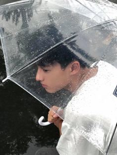 a young man holding an umbrella in the rain