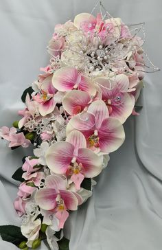 a bridal bouquet with pink and white flowers on a gray cloth covered background,