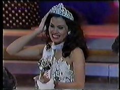 a woman wearing a tiara and smiling at the camera with her hand on her head