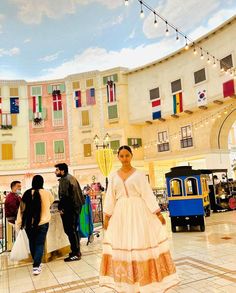 a woman in a long white dress is standing on the tiled floor with other people