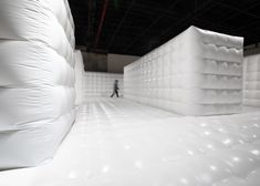 there is a man walking through an inflatable room with mattresses on the walls