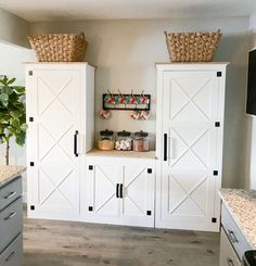 a kitchen with white cabinets and baskets on top