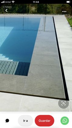 an empty swimming pool surrounded by grass and trees