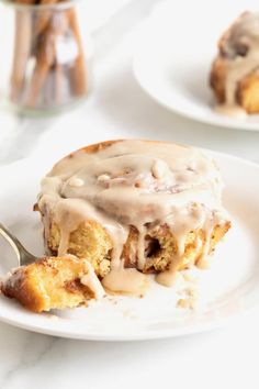 a white plate topped with cinnamon roll covered in icing