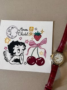 a red watch sitting on top of a piece of paper next to a card with the words moon child