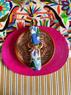 a plate with a napkin on top of it next to a place mat and colorful wallpaper