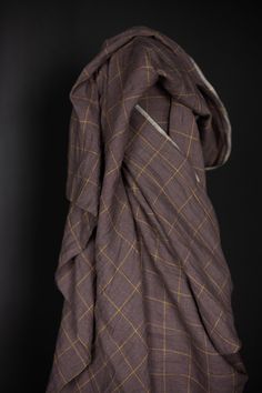 an unbuttoned brown and yellow checkered blanket on a black background with the hood pulled back