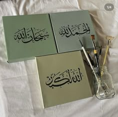 three books with arabic writing on them are sitting on a bed next to a brush