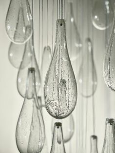 many clear glass vases are hanging from the ceiling with water droplets all over them