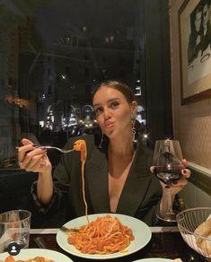 a woman sitting at a table eating spaghetti