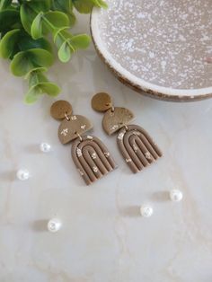 two pairs of earrings sitting on top of a table next to a potted plant