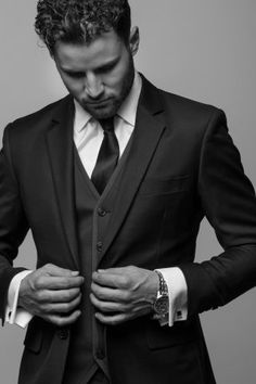 a man in a suit and tie is looking down at his watch on his lapel