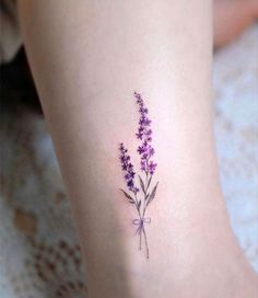 a small purple flower tattoo on the ankle