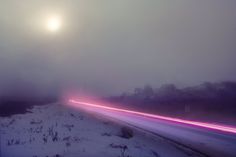 a long exposure photo of a road in the snow